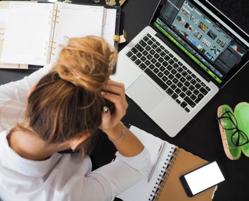 a woman struggling to do work on a laptop