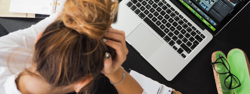 a woman struggling to do work on a laptop