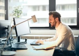 smiling man working at a computer desk in the office