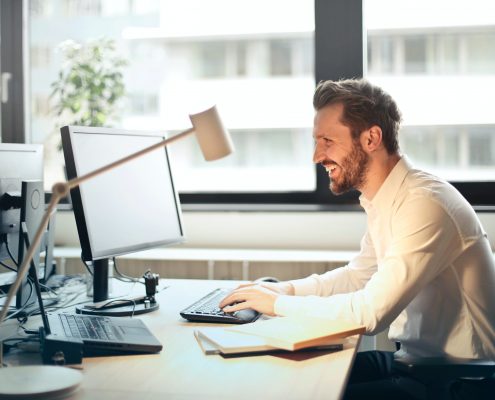 smiling man working at a computer desk in the office