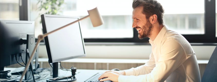 smiling man working at a computer desk in the office